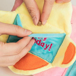 Colorful plush toy with 'Happy Birthday!' text held by hands