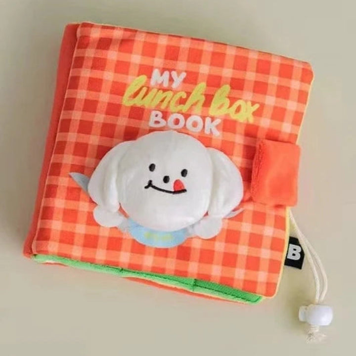 A children's fabric lunch box book with a bright orange and white gingham pattern cover, featuring a white plush dog character on the front and the text 'MY lunch box BOOK' in yellow and white lettering.
